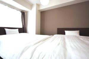 een slaapkamer met 2 witte bedden en een raam bij Suncourt Hongo Dori Garden Hills / Vacation STAY 7620 in Sapporo