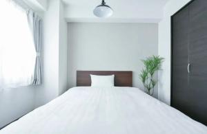 a bedroom with a large white bed with a wooden headboard at Suncourt Hondori Garden Hills / Vacation STAY 7587 in Sapporo