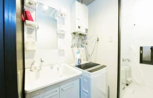 Baño blanco con lavabo y espejo en Suncourt Hondori Garden Hills / Vacation STAY 7584, en Sapporo