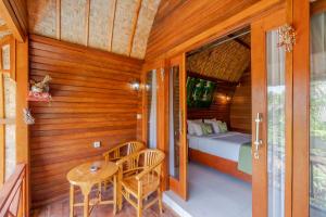 a room with a bed and a table and chairs at Putra Bali Villa by Bukit Vista in Nusa Penida