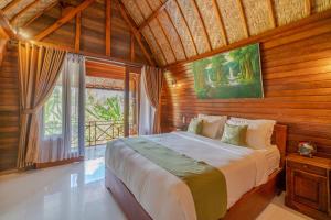 a bedroom with a large bed in a room with wooden walls at Putra Bali Villa by Bukit Vista in Nusa Penida