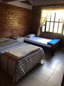 a bedroom with two beds and a window at Hermosa Cabana con bonito Jardin y piscina en la Mesa de los Santos in Los Curos