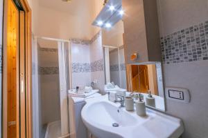 een witte badkamer met een wastafel en een spiegel bij Casa di Paolo 50m from beach - Happy Rentals in Letojanni