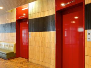 a row of elevators in a building with red doors at Hotel Abest Osu Kannon Ekimae Hane no Yu in Nagoya