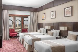 ein Hotelzimmer mit 4 Betten und einem roten Stuhl in der Unterkunft Taiba Front Hotel in Medina