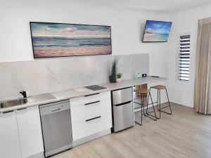 a white kitchen with a counter and a sink at Palm Cove Beach Retreat - 1st Floor in Palm Cove