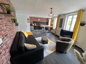 ein Wohnzimmer mit einem schwarzen Sofa und einer Ziegelwand in der Unterkunft Parking - Wifi - Hyper Centre - Cosy - Lumineux in Montivilliers