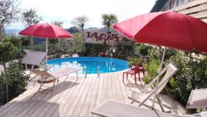 einen Pool mit 2 Stühlen und einem roten Regenschirm in der Unterkunft Agricola Lanciani in Montefiore dellʼAso