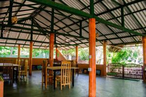 a dining area with tables and chairs in a building at Sarada Beach Resort in Tissamaharama
