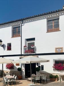 a white building with tables and chairs and umbrellas at Casa Blanca in Castell de Castells