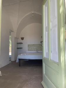 1 dormitorio con 1 cama en una habitación con puerta abierta en I trulli della Masseria del Salento, en Maruggio