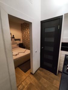 Cette petite chambre comprend un lit et une porte noire. dans l'établissement Ruska Apartments, à Lviv