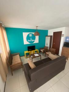 ein Wohnzimmer mit einem schwarzen Sofa und einer blauen Wand in der Unterkunft Por Pipa Casas de Praia - Casa Macao in Pipa