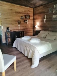 - une chambre avec un grand lit blanc et un mur en bois dans l'établissement LAPAUSEDEGOUT piscine table d'hôtes chambres climatisées terrasse ou patio, à Lachapelle-Auzac