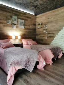 a bedroom with two beds with pink sheets and a staircase at LAPAUSEDEGOUT piscine table d'hôtes chambres climatisées terrasse ou patio in Lachapelle-Auzac