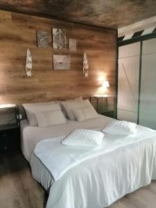 a white bed in a room with a wooden wall at LAPAUSEDEGOUT piscine chambres climatisées terrasse table d'hôtes in Lachapelle-Auzac