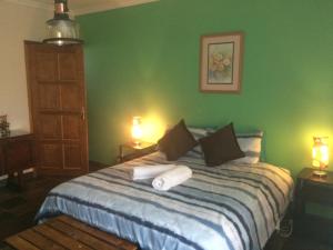 a bedroom with a bed with green walls and two lamps at Edi's B&B and Bratwurst Sausage Restaurant in Balgowan