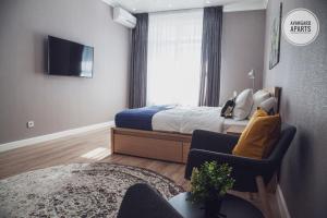 - une chambre avec un lit, une télévision et une chaise dans l'établissement Avangard Aparts - Zaman-2, à Atyraū