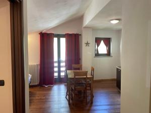 格雷索內伊－拉－特里尼特埃的住宿－Residence Le Marmotte，一间带桌椅和红色窗帘的用餐室