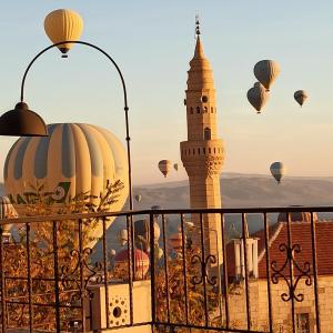 a view of a clock tower and hot air balloons at Alice in Cappadocia in Uchisar +79 photos