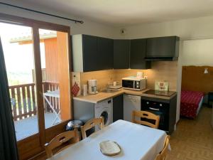 a kitchen with a table and a kitchen with a balcony at le pied des pistes in Puy-Saint-Vincent