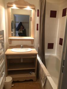 a woman taking a picture of a bathroom with a sink and tub at le pied des pistes in Puy-Saint-Vincent +24 photos