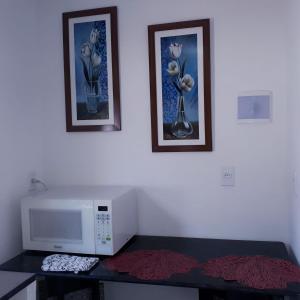 a room with a microwave and two pictures on the wall at Isa Natal 3 Banheiro Privativo in Natal