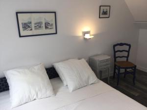 1 dormitorio con 1 cama con almohadas blancas y silla en Gîte de la Fresnais, en Epiniac