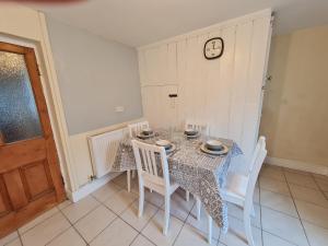 a dining room with a table and chairs and a clock at Charming Cottage style 3 bedroom property in Merthyr Tydfil