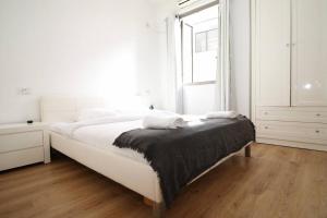 a white bedroom with a large bed and a window at Peaceful Apartment Next To Gordon Beach By Vacay in Tel Aviv