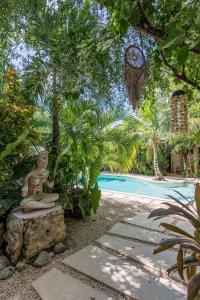 a garden with a statue next to a swimming pool at Trece Lunas in Tulum