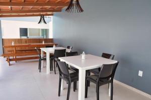 a dining room with white tables and black chairs at Pousada Encanto dos Canyons in Piranhas