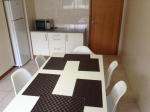 uma cozinha com uma mesa branca e cadeiras brancas em Ramalho Apartments T3 Cidade Ponta Delgada em Ponta Delgada