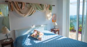 a bedroom with a bed with a blue comforter and a window at Forestata Village in Lixouri