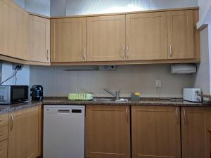 una cucina con armadi in legno e lavastoviglie bianca di Ericeira II - Apartment with Pool - Horizonte Mar a Ericeira Altre 8 foto