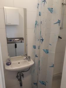 a bathroom with a sink and a shower curtain with blue fish at Monteapartments Vienna Belvedere 10 minutes to downtown in Vienna