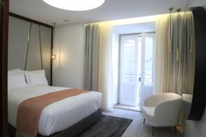 a bedroom with a bed and a chair and a window at São Vicente Alfama Hotel by TRIUS Hotels in Lisbon