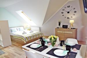 a room with a bed and a table with a clock at Holiday Hill Apartamenty Pogodny, blisko do dworca PKP in Karpacz