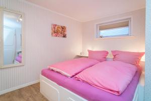 提努姆Schallers Hüs 5 - Bungalow的卧室内的粉红色床和粉红色枕头