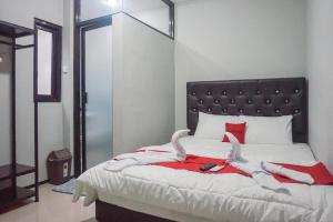 a bedroom with a large bed with red and white sheets at RedDoorz Plus @ Kalpataru in Rampal