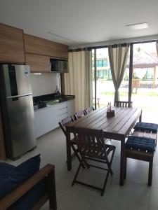 eine Küche mit einem Holztisch mit Stühlen und einem Kühlschrank in der Unterkunft Curta Milagres 31,condominio Morada do Toque in São Miguel dos Milagres