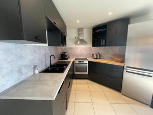 a kitchen with black cabinets and stainless steel appliances at Appartement spacieux avec Sauna, Parking et Jardin - 115 m2 rez de chaussée, 8 couchages in Font-Romeu-Odeillo-Via