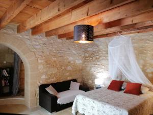 Saint-Hilaire-dʼOzilhanにあるChambre Maison En Pierre Jacuzziのベッドルーム1室(ベッド1台、石壁のソファ付)
