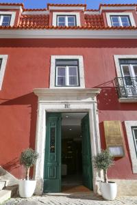 a red building with a green door and two potted plants at Vincci Alfama in Lisbon