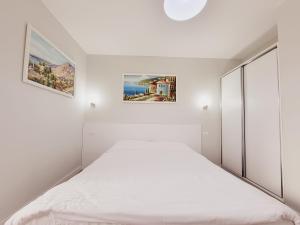 a white bedroom with a bed and a cabinet at Nuestra Casa in Tirana