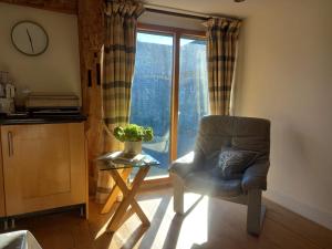a chair and a table in a room with a window at The Barn at Titley in Kington