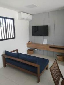 ein Wohnzimmer mit einem blauen Sofa und einem Fernseher in der Unterkunft Curta Milagres 31,condominio Morada do Toque in São Miguel dos Milagres