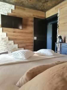 - un grand lit dans une chambre avec un mur dans l'établissement LAPAUSEDEGOUT piscine table d'hôtes chambres climatisées terrasse ou patio, à Lachapelle-Auzac