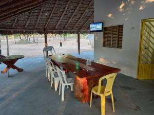 a wooden table with chairs and a television on a beach at Fazendinha Jalapão in Ponte Alta do Norte