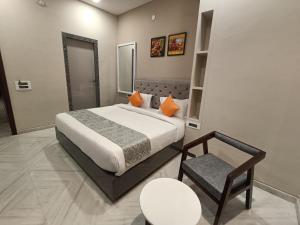 ein Schlafzimmer mit einem großen Bett und einem Stuhl in der Unterkunft Hotel Shri Anand Dham, Nathdwara - 125 Meters away from the temple in Nāthdwāra